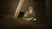 Nogales, AZ: An armed agent climbing through an underground tunnel. Four feet underneath Nogales, Arizona, Border Patrol agents rush to secure a drug smuggling tunnel.