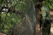 Brownsville, TX, USA: A U.S. Border Patrol agent looking through a fence.