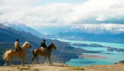 Zwei Gauchos reiten auf Wildpferden und blicken auf die endlose Weite Patagoniens.