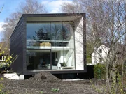 Die Südseite des Hauses mit der großen Glasfront und dem Balkon.