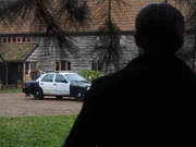 Jason watching the house from the bushes while police car is parked in front.