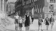 Kinder laufen auf der Straße zwischen den Ruinen.