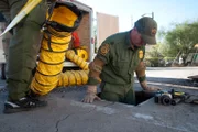 Nogales, AZ: An agent climbing into the entrance of the underground tunnel. While inspecting this tunnel, Border agents must be prepared to encounter smugglers.