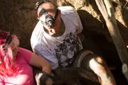 DURBAN, SOUTH AFRICA- A Southern African python (Python natalensis) being handled by Simon Keys, a snake catcher in Durban, KwaZulu-Natal. Simon is removing the snake from within an underground tunnel, with the help of Susan Gillett, Simon's girlfriend and partner in snake catching.