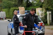 Hans (Bruno F. Apitz, r.) versucht ein Alibi zu widerlegen, in dem er die Strecke zur Schule mit einem Fahrrad abfährt, während Franzi (Rhea Harder, l.) unwillig auf ihn wartet.