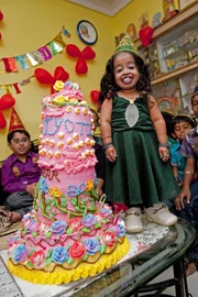 NAGPUR, INDIA - DECEMBER 08: Jyoti Amge poses for a picture with her 18th birthday cake on December 08, 2011 in Nagpur, India.

A teenager the size of a large watermelon became the world?s smallest woman after turning 18 today (FRIDAY).  Tiny two feet tall Jyoti Amge, of Nagpur, India, celebrated the occasion with a birthday cake almost as big as her.  Jyoti, who was already widely regarded as the world?s smallest girl, is anxiously waiting for confirmation she has grabbed the title from 2ft 3in American record holder Bridgette Jordan.

PHOTOGRAPH BY Richard Grange / Barcroft India