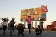 The group in front of the south of the border sign.