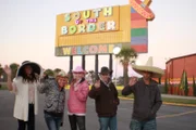 The group in front of the south of the border sign.