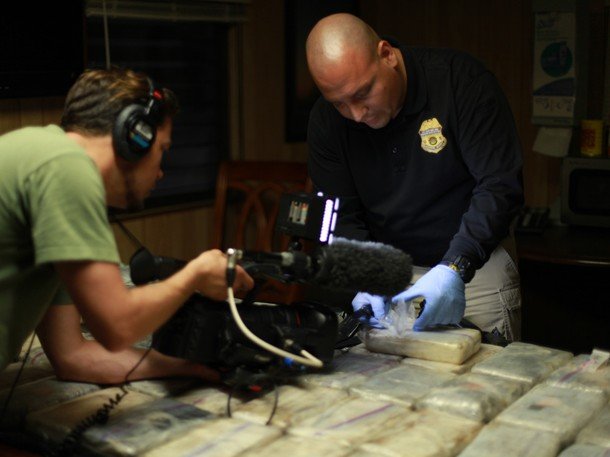 The cameraman shoots a CBP officer opening a package of cocaine.