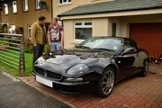 Wide shot of Maserati on front driveway with Mike and seller standing behind it
