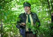 Staller (Helmfried von Lüttichau) bahnt sich den Weg durch den Wald bis zum Seeufer, wo ein aufgeregter Spaziergänger ein Krokodil gesehen haben will.