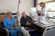 Karl Hildebrandt (Ernst Stankovski, Mitte) muss häufiger in die anstrengende Dialyse als zuvor, doch Hildegard Jürgens (Edith Behleit, l.) versucht ihr Bestes, um ihn abzulenken. R: Komparsin.