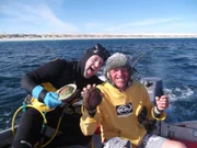 Abalone Sheller Tony Custance and Abalone Diver Jay Haagmans on boat holding up fresh caught abalone.