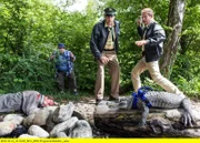 Der Passant (Roberto Martinez, links) führt Hubert (Christian Tramitz, rechts) und Staller (Helmfried von Lüttichau) zu dem Krokodil. Hubert wirft einen Stein um zu testen, ob der Kaiman noch lebt. Da entdecken sie, dass neben dem Kaiman der tote Tobias Brunner (Komparse) liegt.