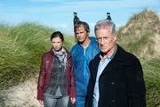 Hauptkommissar Theo Clüver (Robert Atzorn, r.) und seine Kollegin Ina Behrendsen (Julia Brendler, l.) lassen sich am Fundort der Leiche von dem Gerichtsmediziner (Josh Broeker) aufklären.