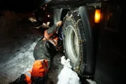 Eidfjord, Norway - Bjoern Laegreid is putting on chains on the truck. This will probably help the truck to drive on the slippery road.