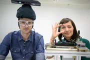 Die „Xenius“-Moderatoren Emilie und Adrian im Zeiss Vision Science Lab: Hier werden besondere Brillengläser produziert und getestet.