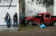 Police stand near a car with the body of a dead man at a crime scene on the outskirts of Guadalajara September 28, 2010. According to local media, two people were killed during the attack by gunmen outside a public school in a residential area on the outskirts of the city.