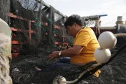 Hainan, China - Mr. Li helps mend the fishing net, needing to provide for his 18 member household. (National Geographic/Liu Fang)