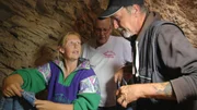 Anita sucht sich Kleidung aus, die Udo (M.) von der Suchthilfe mitgebracht hat, Detlef schaut zu