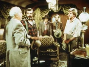 Der Präsident der Eisenbahngesellschaft, Mr. Hollingsworth (Stephen Elliott, l.), bittet Almanzo Wilder (Dean Butler, r.) und Mr. Edwards (Victor French, 2.v.l.) um ihre Mitarbeit bei seinem Projekt.