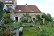 The contributors' property has a lovely backyard that comes with old masonry, a pond, and overgrown plants and ivy around the perimeter, as seen on HGTV's House Hunters International Renovation.