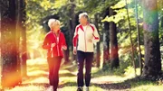 Senior Couple doing sport outdoors, jogging on a forest road in the autumn