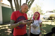 DURBAN, SOUTH AFRICA- Simon Keys and Susan Gillett standing next to a house in Durban, Simon holding a Brown house snake (Boaedon capensis), while examining it. Simon and Susan catch snakes in human habitations in and around Durban and translocate them to safer areas where they are less likely to come into contact with people. (Photo credit: National Geographic Channels/Frederick Higgs)