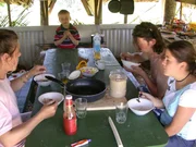 Familie Kinder in ihrer Kochhütte beim Essen.