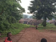 Shot of the road leading into a village while children smile at the camera.