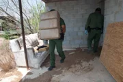 Brownsville, TX, USA: A Border Patrol agent carries out bundles of cofiscated contrband from a house.