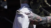 Durban, South Africa - Close up shot of Simon Keys hands, demonstrating one of the most dangerous aspects of a snake capture: bagging the snake. The method Simon uses to 'bag' a snake, involves him putting his right hand into the bag and carefully swapping his grip on the snake's head, in this case, the highly venomous black mamba (Dendroaspis polylepis), then flipping the bag over the snake, and finally securing the open end with tape.