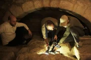 Josh Gates and Director of Photography Brian Weed filming the tombs beneath the Church of the Nativity as Biblical Scholar Haytham Dieck watches in Bethlehem, West Bank.