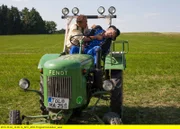 Hubert (Christian Tramitz, links) und Staller sehen, dass ein Traktor auf dem Feld im Kreis fährt. Sie möchten den Fahrer darauf aufmerksam machen, doch dieser reagiert nicht. Hubert springt auf den Traktor und muss erkennen, dass der Fahrer, Bauer Ernst Poschinger (Komparse) erschossen wurde.