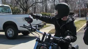 Max Wade holding a gun up to a white pickup truck.