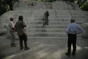 Dr. Richard Hansen, Josh Gates, and Bob Leonard watch Robert Leonard examine the steps of an ancient Mayan structure with a GPR device in Guatemala.