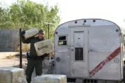 Roma, Texas, USA: Border Patrol Agent Kellen Meador carrying large bundles of marijuana found in an abandoned house, and piling them in front of an old trailer. (Photo Credit: (NGT)