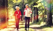 Senior Couple doing sport outdoors, jogging on a forest road in the autumn