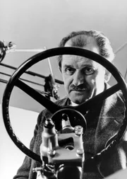 Ferdinand Porsche posiert hinter dem Lenkrad eines VW.