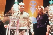 Dale (Colin Mochrie, l.) will auf der zehnten Jahrestagung der "Nordamerikanischen UFO-Gesellschaft" eine Überraschung präsentieren: das Wrackteil eines außerirdischen Raumschiffs. Boo (Mackenzie Phillips) ist auf die Reaktionen gespannt.
