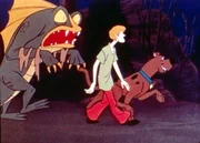 Shaggy (M.) und Scooby-Doo (r.) gehen am kanadischen "See ohne Grund" spazieren und ahnen nicht, dass das furchterregende Seemonster (l.) direkt hinter ihnen ist...