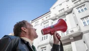 Franz Hubert (Christian Tramitz) spricht über das Megaphon mit der lebensmüden Anna Schmitt, die von ihrem Balkon springen will.