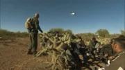 Nogales, AZ: An agent signaling to a helicopter in the air, while a group of apprehended men sit on the ground. Helicopters have been beneficial in conducting high speed chases.