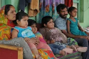 Family photograph of Amisha, Yogita and Harsh Nandwana with their sister Bhavika, mother Pragnaben and father Rameshbhai Nandwana sitting down on a couch.