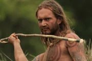 Close up of Darrin aiming his spear at the camera.