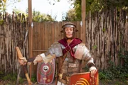 Checker Tobi in Legionärsausrüstung vor einem Castrum.