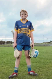 Mac mit seiner Hurling-Ausrüstung: Helm, Hurley (Schläger) und Sliotar (Ball)