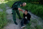 Laredo, TX: An agent giving a handcuffed man water. Dehydration is a dangerous possibility when crossing the border.  (Photo Credit: © NGT)