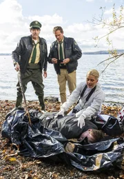 Am Haken eines Schwarzfischers hing eine Leiche im Plastiksack (Komparse). Hubert (Christian Tramitz, M.) und Staller (Helmfried von Lüttichau, l.) versuchen mit Hilfe von Pathologin Dr. Licht (Karin Thaler, r.) den Toten zu identifizieren.