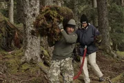 Henry carries heap of moss on shoulder.